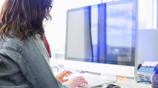 zijaanzicht van een vrouw aan het werk achter een computer op een kantoor