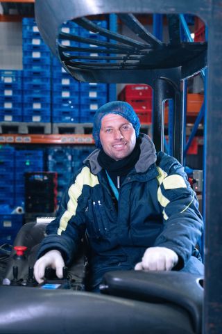 Mathia, werknemer van Dekeyzer-Ossaer, aan het rijden met de heftruck in het magazijn